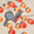 Spicy Girl No-Plumper Lip Gloss lifestyle flat lay on white marble with orange petals