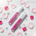 Diamond Kisses Kiss Me Lip Gloss lifestyle flat lay with crystals and pink roses
